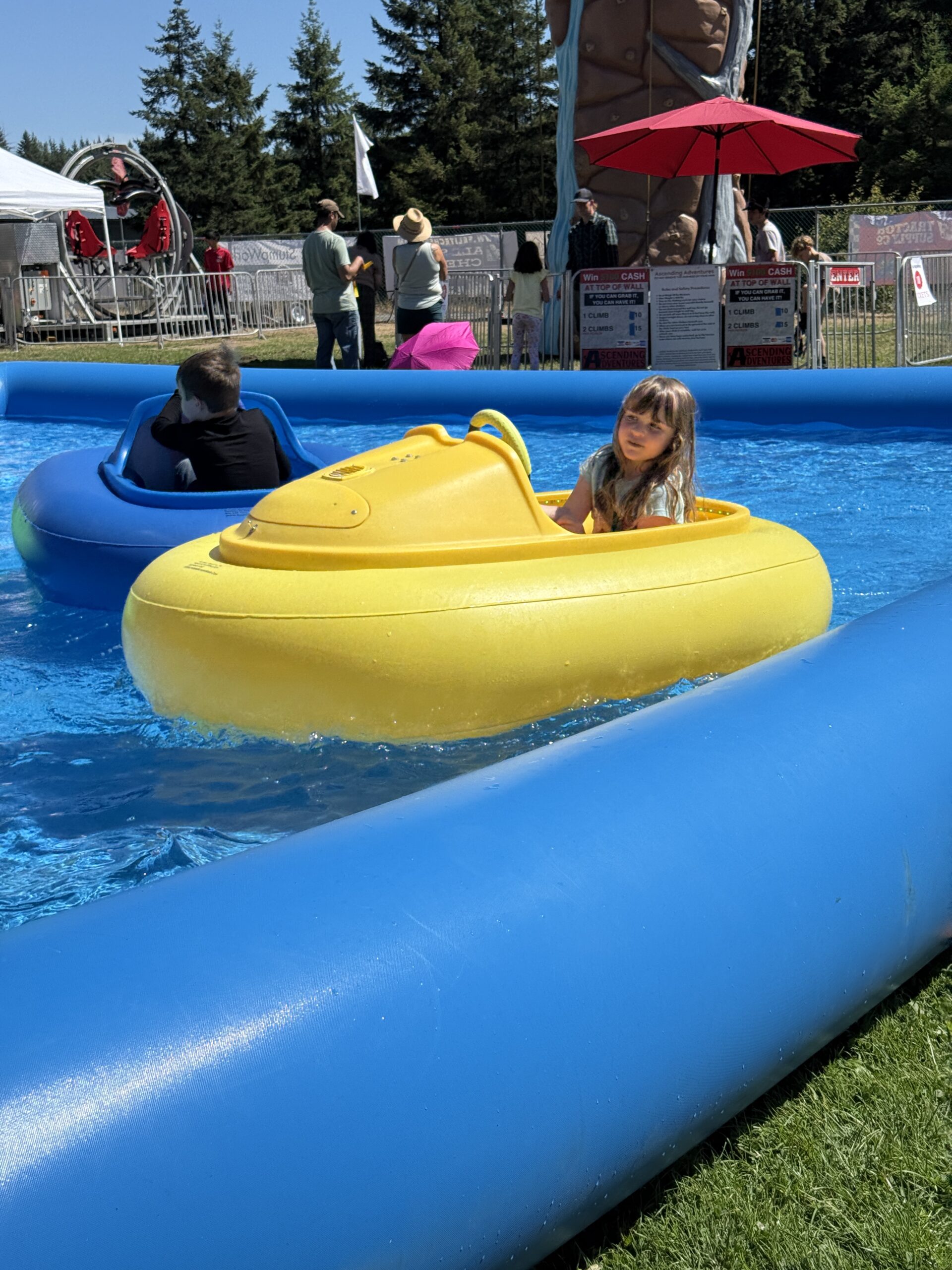 Children ride blue and yellow bumper boats in a shallow pool at the Fair.