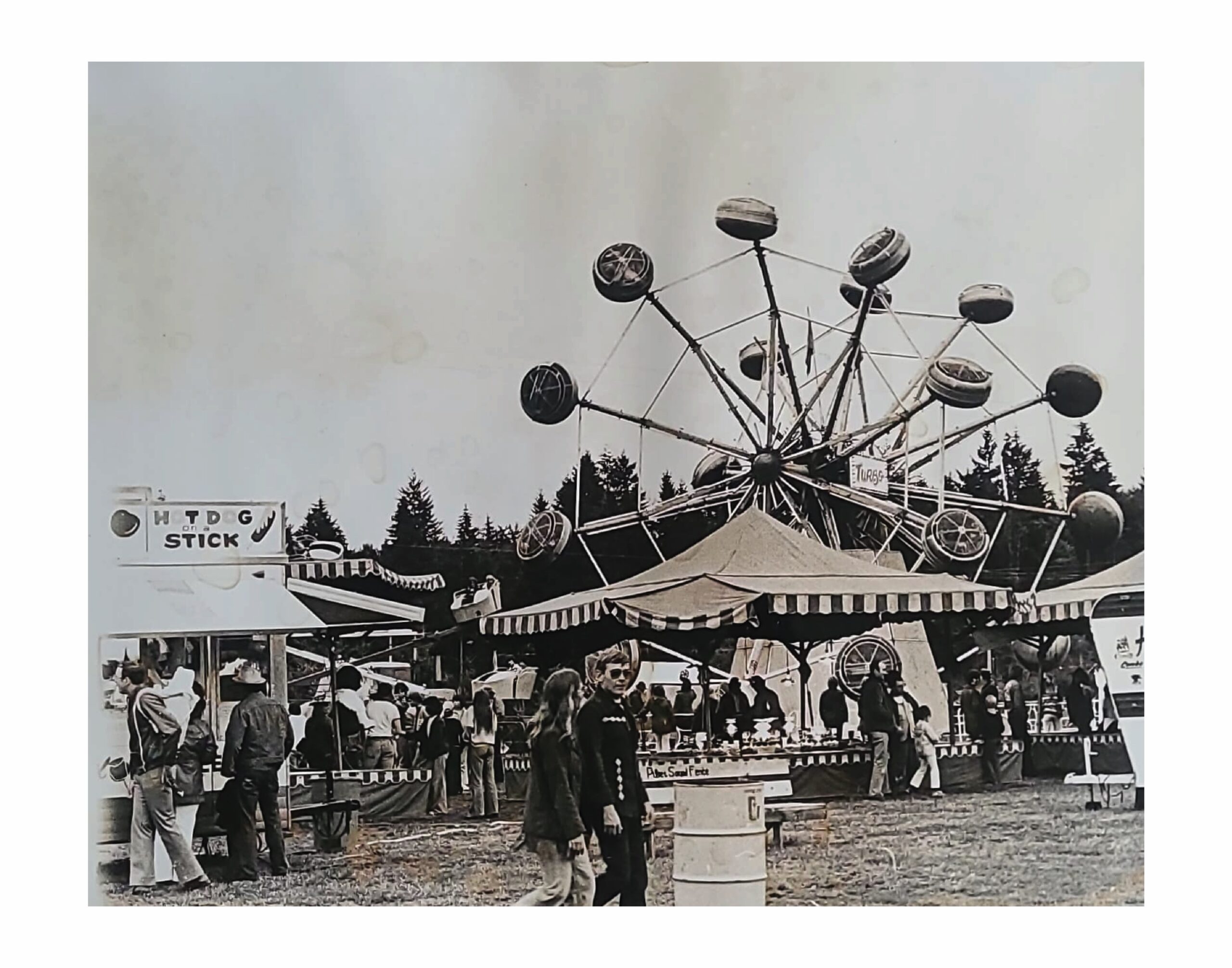 Historical photograph of visitors, food stands and a carnival ride at the Fair.
