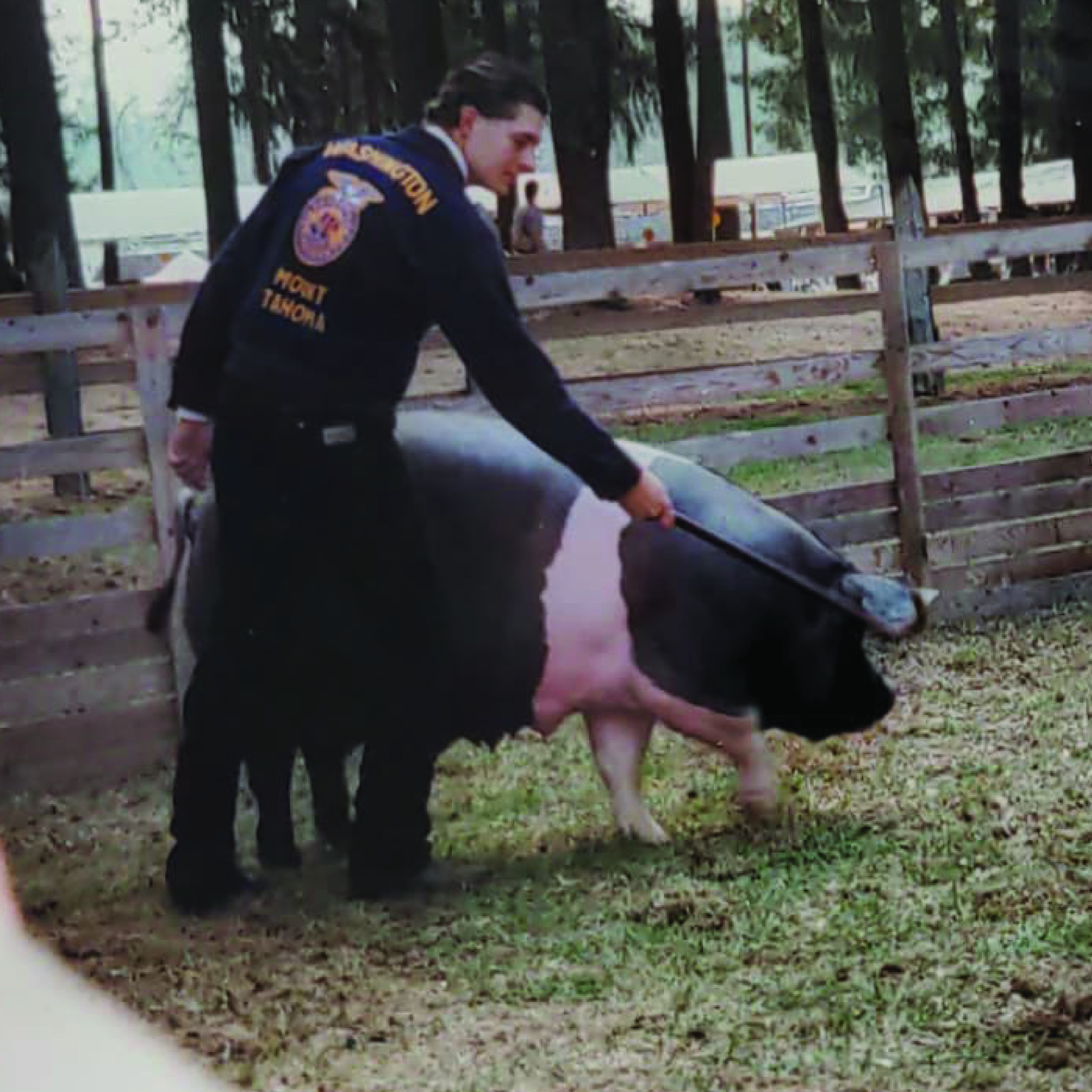 Historical photograph of an FFA exhibitor showing a pig in an outdoor ring.