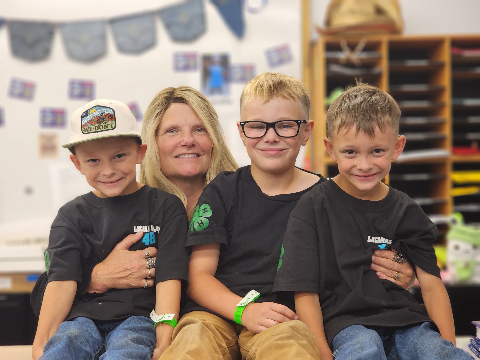 Family smiling together at the Fair, with children wearing 4-H shirts.