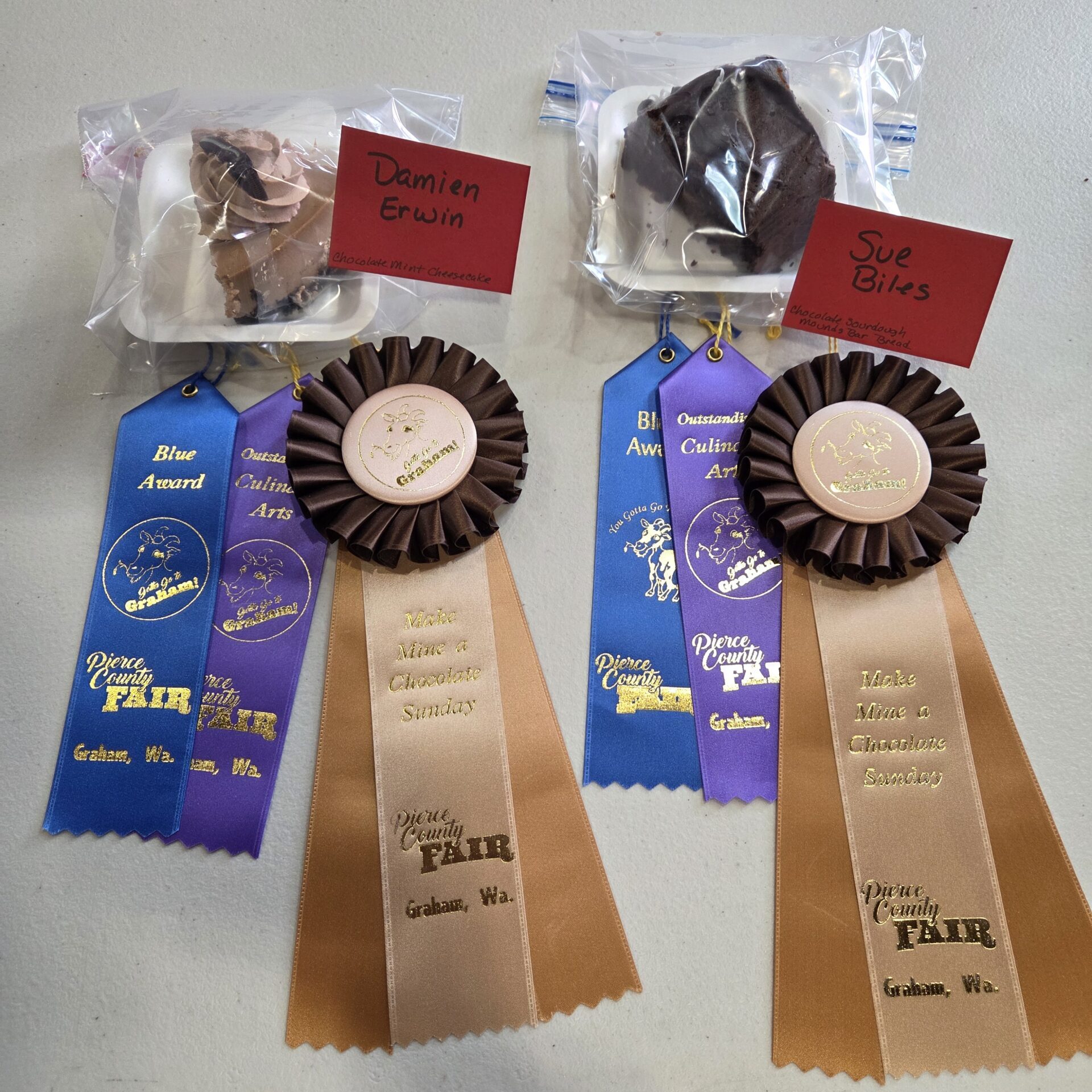 Two chocolate contest entries are displayed with blue, purple, and brown award ribbons.