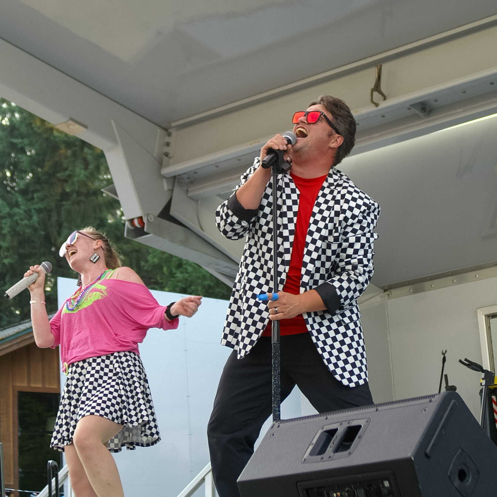 Two singers in colorful outfits perform on an outdoor stage at the Pierce County Fair.