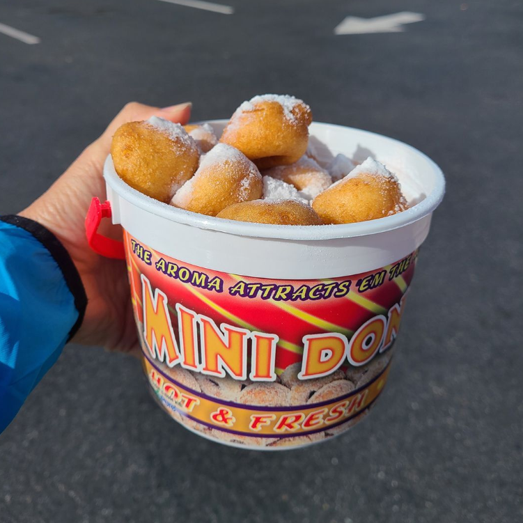 A hand holds a bucket of sugar-coated mini donuts at the Fair.